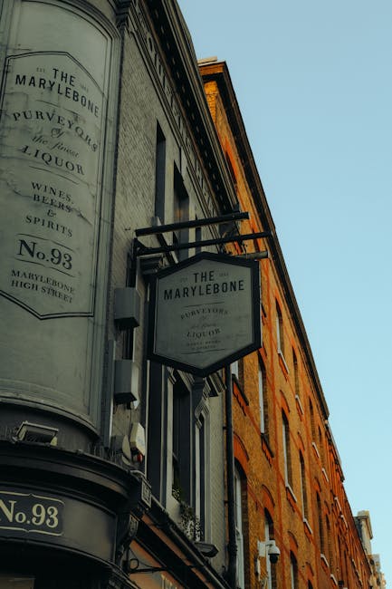 Photograph of the exterior of a historic building on Marylebone High Street, featuring a large, vintage-style sign with the text 'The Marylebone' and details about liquor, wines, spirits, and location